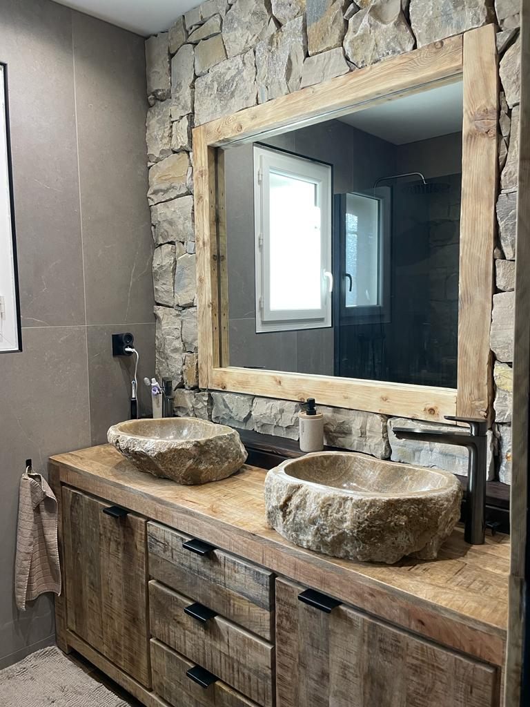 Salle de bain avec mur en pierre sèche, deux vasques en pierre brute sur meuble bois massif